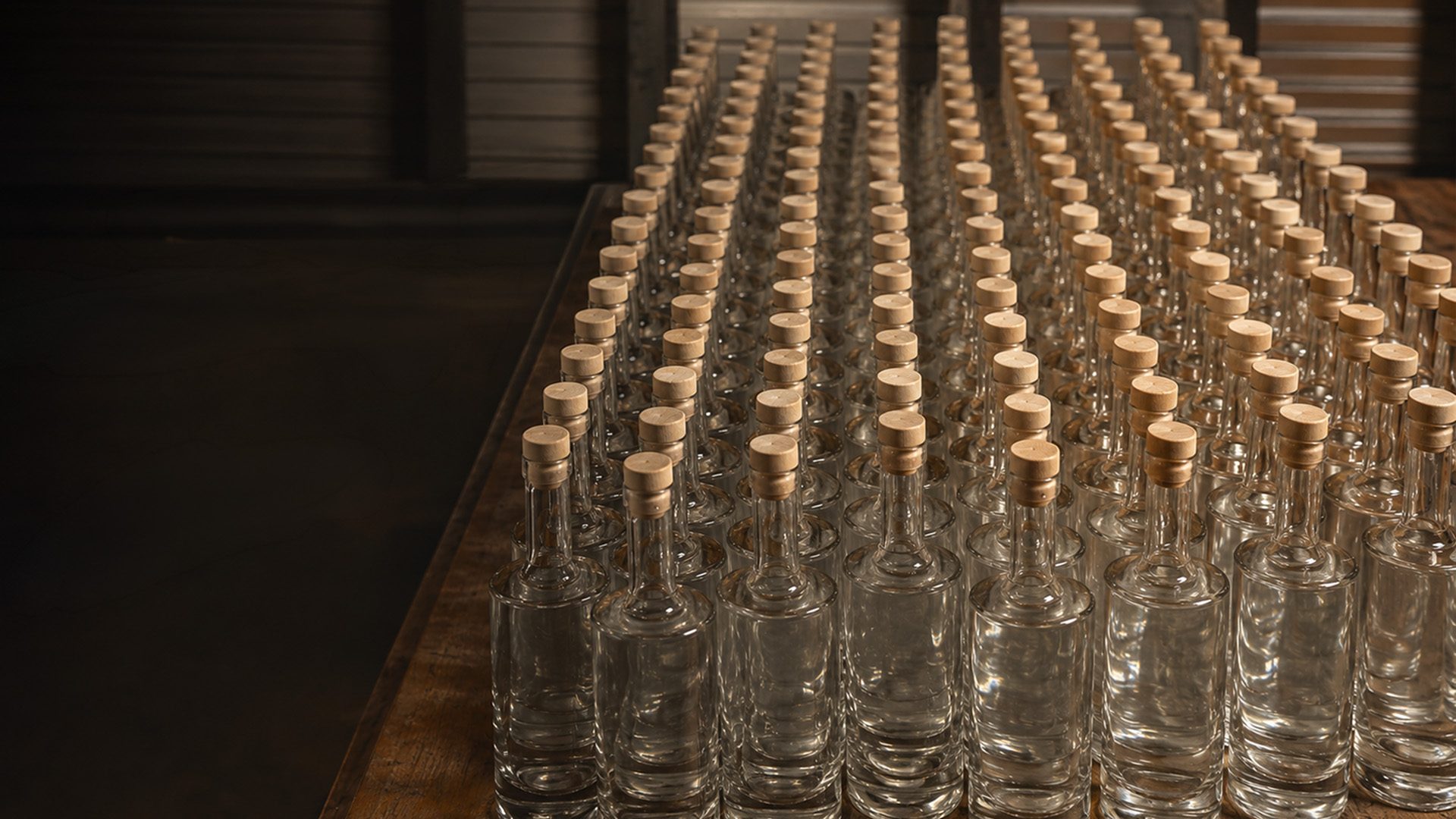 Hundreds of empty Superfly bottles lined up on a wooden bottling table at the distillery in Brookings, Oregon