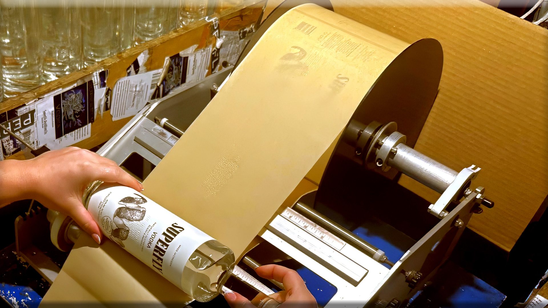Hands placing a label on a Superfly bottle at the distillery